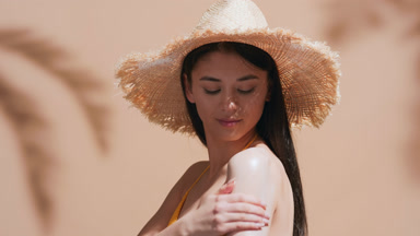 Young woman applies sunscreen on shoulder and enjoys the sun