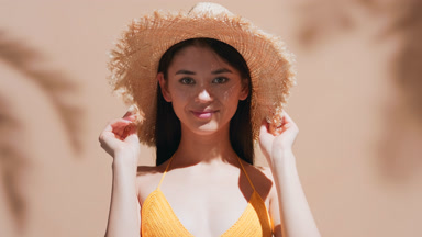 Young woman in yellow swimsuit enjoys the sun and smiles