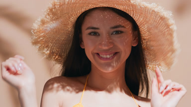 Woman in a straw hat enjoys the sun and blows a kiss to the cam