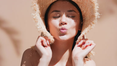 Young female model in a straw hat blowing a kiss for the camera