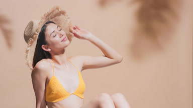 Young Asian woman in a straw hat enjoys the sun sunbathing
