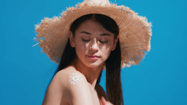 Young woman putting sunscreen on shoulder smiles for the camera