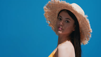 Asian girl in a straw hat turns around and smiles for the camera