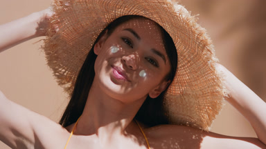 Young Asian woman with sunscreen on her cheeks blows a kiss