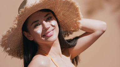 Young woman with sunscreen on her cheeks turns around smiling