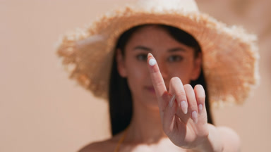 Young Asian woman shows a drop of sunscreen cream on her finger