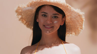 Asian woman shows a drop of spf cream and applies it to her face