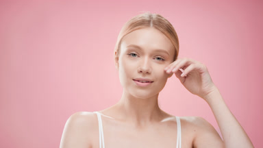 Woman with light hair turns head to the camera touching cheek
