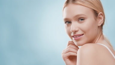 Pretty blonde woman turns head touching shoulder and smiling