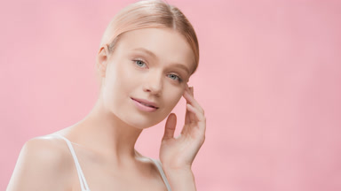 Woman with light hair in ponytail touches jawline turning body