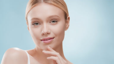 Slim blond woman turns to the camera touching face and smiling