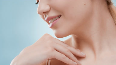 Woman touches collar bone and turns head looking at the camera