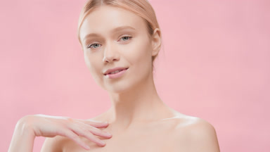 Blonde woman touches her clavicles turning her body and smiling