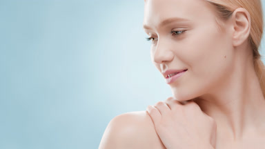 Pretty blond woman touches shoulder and turns head smiling wide