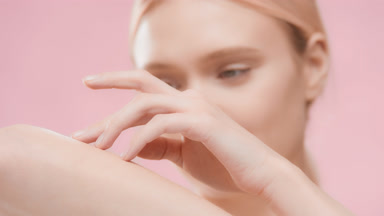Young European woman touches arm and looks at the camera smiling