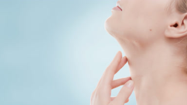 Beautiful woman in white top lifts head up and touches neck