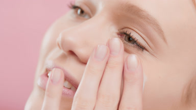 Beautiful woman puts moisturizer on face smiling wide for camera