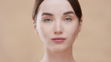 Young woman opens eyes moving head up and looking at the camera