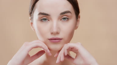 Slim gorgeous brown-haired woman opens eyes touching her jawline