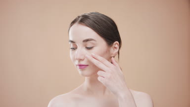 Beautiful woman touches cheek with fingers looking at the camera