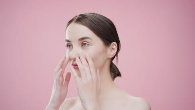Woman touches cheeks and jawline with fingers turning to camera