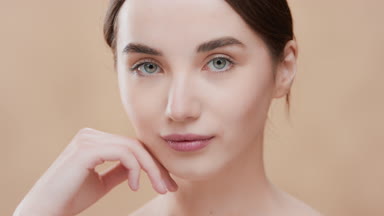 Girl touches jawline with fingers smiling and looking at camera