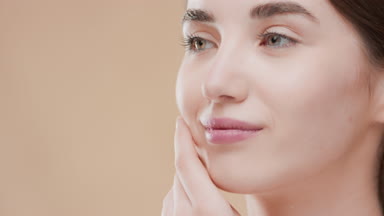 Caucasian woman touches cheek and chin with hand and turns head