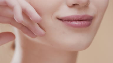 Cute female model touches face and smiles wide for the camera