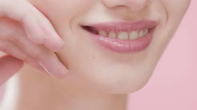 Pretty female model touches her face smiling wide for the camera