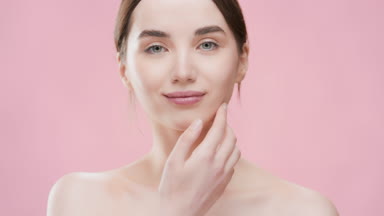 Beautiful slim dark-haired woman touches jawline turning body
