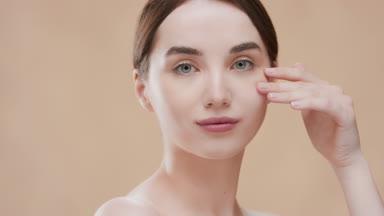 Fit woman touches her nose and cheek smiling wide for the camera