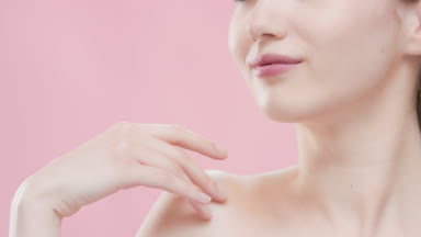 Brunette woman touches clavicle and turns head to the camera