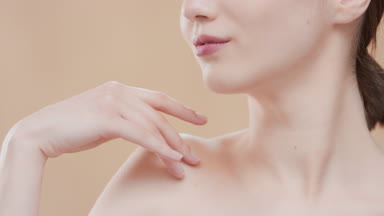 Brown-haired girl touches clavicle and turns head to the camera