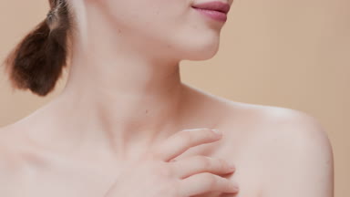 Dark-haired female model touches her clavicles turning her head