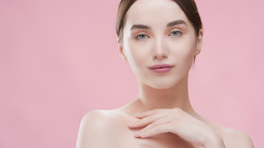 Slim woman touches clavicles turning body and looking at camera