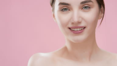 Gorgeous woman touches shoulder and looks at the camera smiling