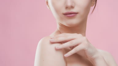 European woman touches shoulder and clavicles and smiles wide