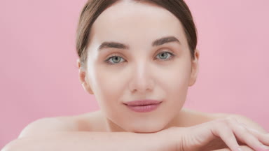 Caucasian woman puts head on arm looking at camera and smiling
