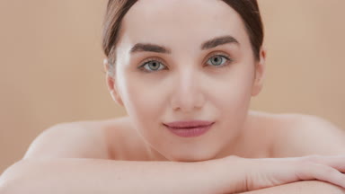 Attractive woman puts head on arm looking at camera and smiling