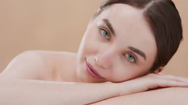 Brown-haired fit Caucasian woman turns her head lying on her arm