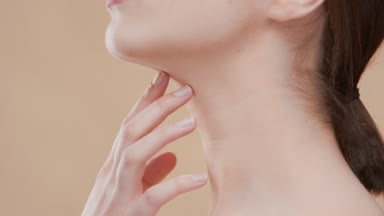 Pretty young slim woman touches neck with fingers and turns body