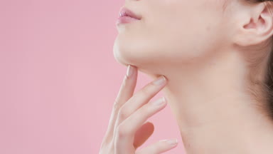 Attractive female model touches neck with fingers and turns body