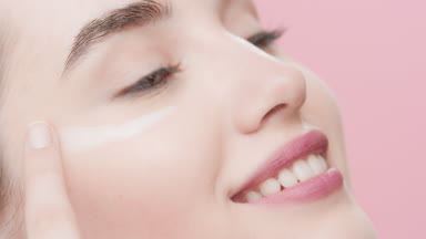 Beautiful young Caucasian woman applies day cream under her eye