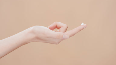 Model lifts her hand with a drop of moisturizer on forefinger up