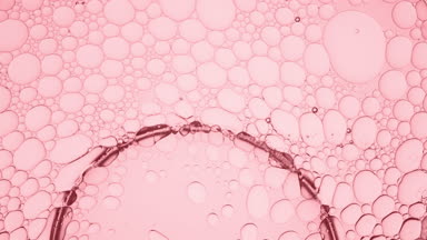Big clear bubble slides along pale pink smaller ones moving them