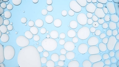Light grey different sized bubbles move slowly in clear liquid