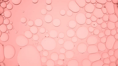 Pale pink different sized bubbles float in clear liquid