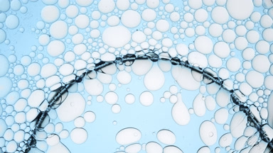 Transparent bubble moves along pale blue smaller ones and bursts