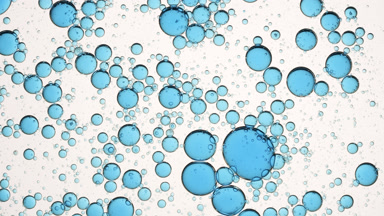 Blue different sized bubbles move in circles in clear fluid