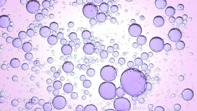 Purple different sized bubbles swirl in clear liquid